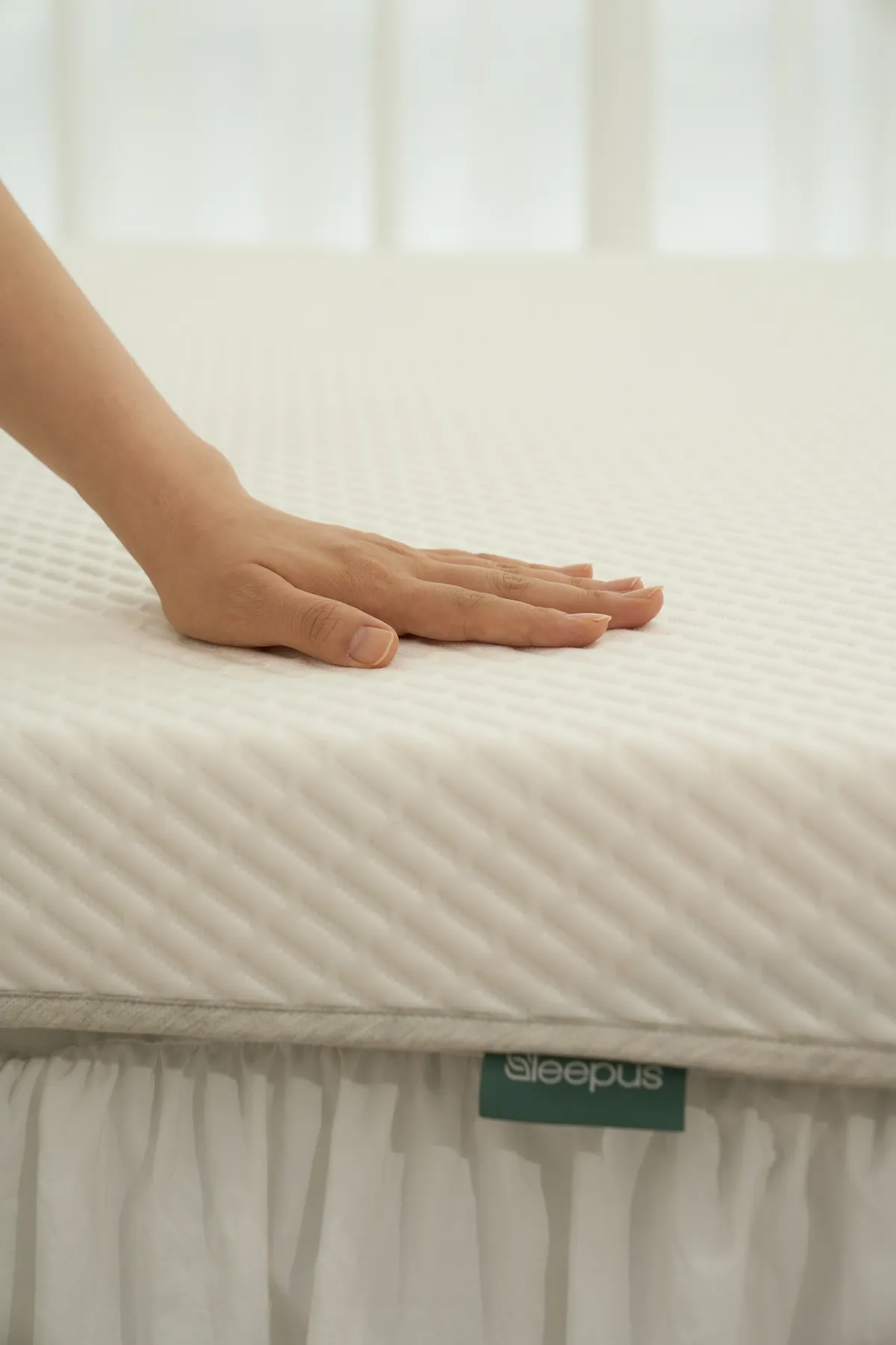 손으로 Sleepus 매트리스를 눌러보는 모습 — 탄성과 복원력